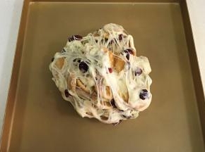把雪花酥团倒入不粘烤盘内，用双手不停往外翻，直到饼干和坚果料都被千丝万缕的糖包裹住。