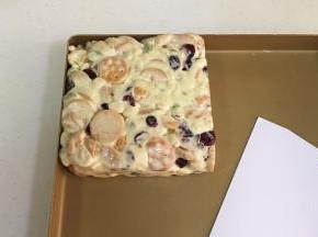 带上一次性手套慢慢推压紧实雪花酥团，然后进一步借用塑料刮板整形成方形。