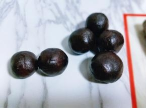 取一块豆沙馅，将蛋黄包起来，豆沙蛋黄馅包起来，如图。