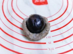 取一块切好的面团，用手掌心压扁，再用擀面杖擀薄，包上豆沙蛋黄馅。