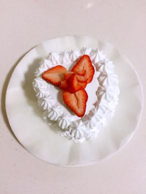 在蛋糕胚表面抹上奶油，边缘用裱花嘴挤出纹路，草莓切开摆在中间。