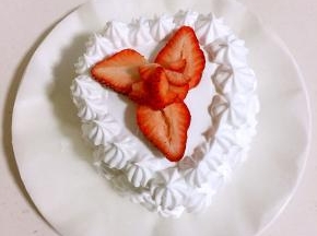 在蛋糕胚表面抹上奶油，边缘用裱花嘴挤出纹路，草莓切开摆在中间。