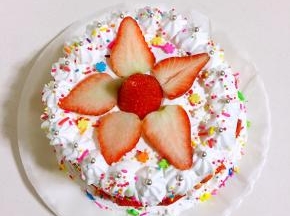 在第一片蛋糕上，抹上打发好的奶油，盖上第二片蛋糕再抹上奶油，盖上第三片蛋糕，并用奶油将蛋糕整体抹均匀。用裱花嘴在蛋糕顶部一圈挤上花纹，再在蛋糕底部边缘也挤上花纹，把切好的草莓摆在中间，蛋糕四周也均匀的贴一圈草莓片装饰一下，最后撒上适量的彩糖装饰即可。