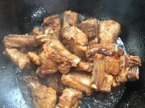 放入排骨，调中火，快速的翻炒，使每一根排骨都均匀的裹满糖色。