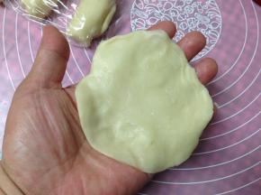 对折的方向朝上，用手压扁，再用擀面杖擀成边缘薄，中间厚的圆形
