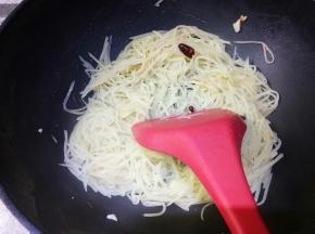 翻炒均匀，倒入一勺水，这里勺子是盛汤用的大勺子。为啥倒水呢，因为经过翻炒土豆内部的淀粉析出了，会发粘，如果是普通锅会粘锅，倒这一勺水到土豆成熟出锅正好没有汤汁而又不会发粘。汤汁收完，土豆丝正好熟，而且还保持脆的口感