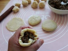 取一个小面剂擀圆（案上和擀面杖上用一点点薄粉），放入馅料约20克包起来。
捏合处做为底面，轻轻地按扁，整理成圆饼。