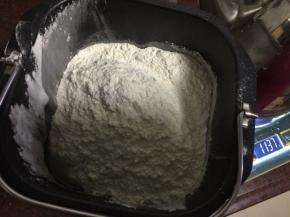 面粉和全麦粉放入面包机中，边搅拌边倒入开水