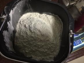 面粉和全麦粉放入面包机中，边搅拌边倒入开水