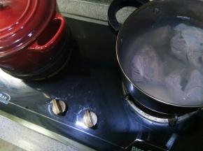 另起一个锅，放半锅水，把洗净的牛腱子放进去焯，把剩余的血沫都焯出，然后捞出牛腱子用温水清洗干净。旁边红色铸铁锅就是正在闷的香料汤。
