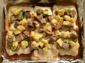 把已经烤了5分钟的吐司披萨从烤箱取出，把吐司碎铺在上面。放入烤箱200度中层继续烤20分钟。