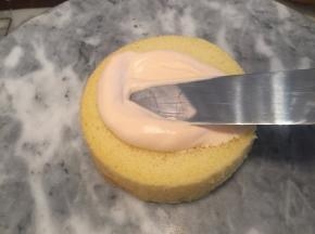取适量的奶油涂抹在蛋糕上，均匀的摊开