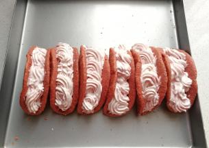 再把草莓奶油挤入定型好的小卷中，先挤一层直条，再随意挤一层花型，最后摆上几块草莓筛上糖粉装饰即可；（因为奶油中有颗粒草莓，所以挤花时会堵不流畅，挤得有点难看，但好吃就行哈！有草莓颗粒口感更丰富）