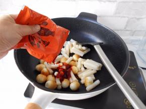 加入炒年糕料包。（如果没有现成的料包，请用韩式辣椒酱、辣椒粉、生抽、白糖、鱼露、和少许清水混合均匀成酱料备用, 或者只用韩式辣椒酱即可，放点洋葱炒炒味道更赞）