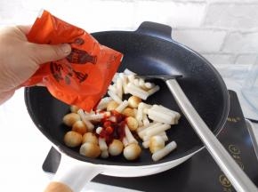 加入炒年糕料包。（如果没有现成的料包，请用韩式辣椒酱、辣椒粉、生抽、白糖、鱼露、和少许清水混合均匀成酱料备用, 或者只用韩式辣椒酱即可，放点洋葱炒炒味道更赞）