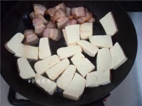 将煎好的五花肉推向一边，利用五花肉渗出的油脂煎豆腐，略煎片刻