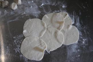 取一个剂子，用手掌按一下，擀成圆片；