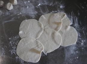 取一个剂子，用手掌按一下，擀成圆片；