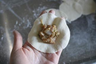 取一个面皮，放入适量肉馅；