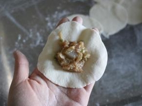 取一个面皮，放入适量肉馅；