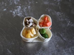 将香菇、玉米、胡萝卜、豌豆粒分别填入孔中；