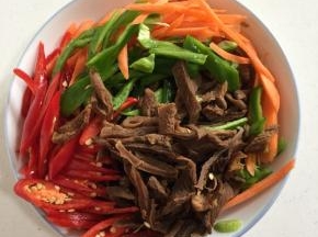 浸泡好的萝卜干挤干水分切成条，红尖椒和青椒切成丝，胡萝卜也切成丝备用。