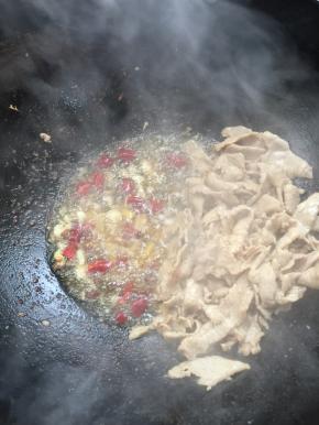把肉片拔在一边，放入蒜瓣，生姜，花椒和干辣椒炒出香味来。