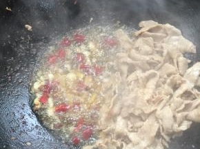 把肉片拔在一边，放入蒜瓣，生姜，花椒和干辣椒炒出香味来。