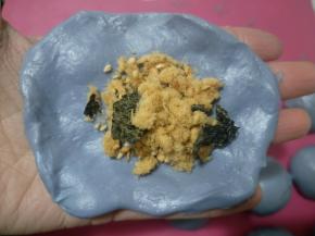 取一个面团按扁，包入适量肉松，像包包子一样包好，收口朝下。