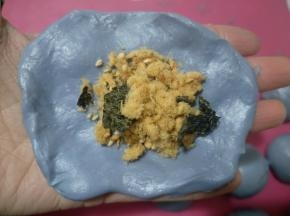 取一个面团按扁，包入适量肉松，像包包子一样包好，收口朝下。