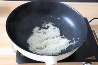 热锅冷油，倒入白萝卜丝炒熟；