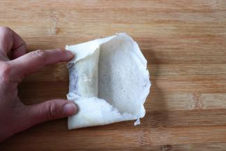 先卷起一边，再将两边向中间折起；