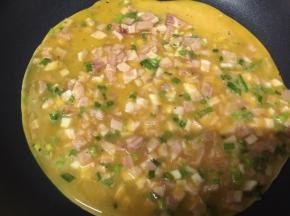 小火，热锅冷油，倒入香菜培根鸡蛋液
迅速均匀摊平