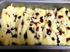 放在温暖湿润处二次发酵至两倍大（模具的8-9分满），面包胚表面刷上剩下的黄油酱炼乳和果干，撒上适量杏仁片，烤箱190度预热