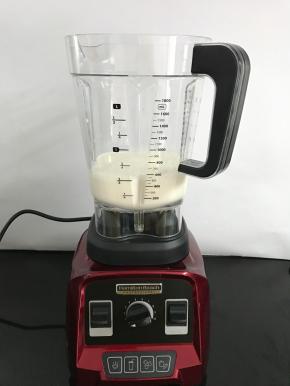 破壁机搅拌杯中倒入牛奶。