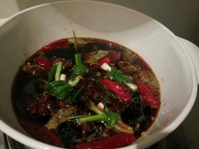 炒好的调料倒入炖锅，加适量清水，烧开，放几个葱结