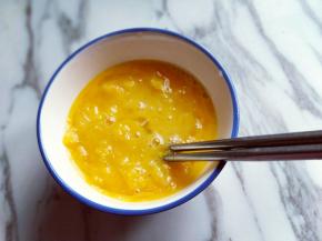 将橙子果肉和果汁一起倒入鸡蛋碗中，加入一点点糖。