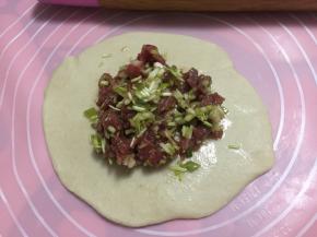 然后用擀面杖将面皮擀成中间厚边缘薄，包入牛肉馅