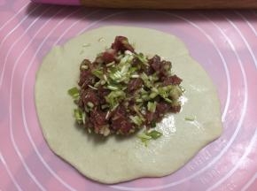 然后用擀面杖将面皮擀成中间厚边缘薄，包入牛肉馅