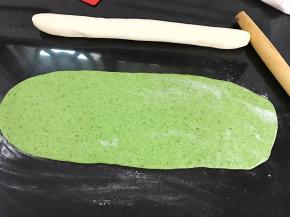 面团醒好后，把白色面团搓成长条，绿色面团擀成和白色面团长短一样的面片。