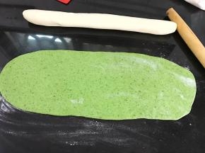 面团醒好后，把白色面团搓成长条，绿色面团擀成和白色面团长短一样的面片。