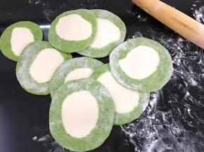 然后取一个剂子按扁，擀成四周薄中间厚的饺子皮。