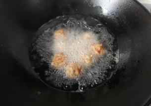 锅中入适量油烧至五成热，放入丸子小火炸，中途用筷子翻拨几次