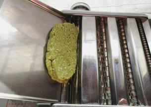 把切好的厚面片放入压面机，调节合适的档位来回压面