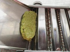 把切好的厚面片放入压面机，调节合适的档位来回压面