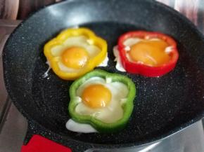 再把鸡蛋敲在彩椒圈里。