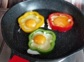 再把鸡蛋敲在彩椒圈里。
