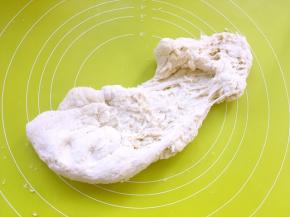 之后倒在揉面垫上，加入中种面团，用手掌一起向前推揉面团，将两种面团推揉均匀