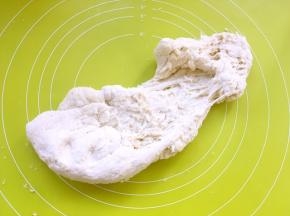之后倒在揉面垫上，加入中种面团，用手掌一起向前推揉面团，将两种面团推揉均匀