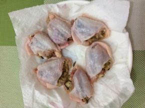 将晾凉的米饭都塞入鸡翅中，然后放在厨房纸巾上吸一下水份